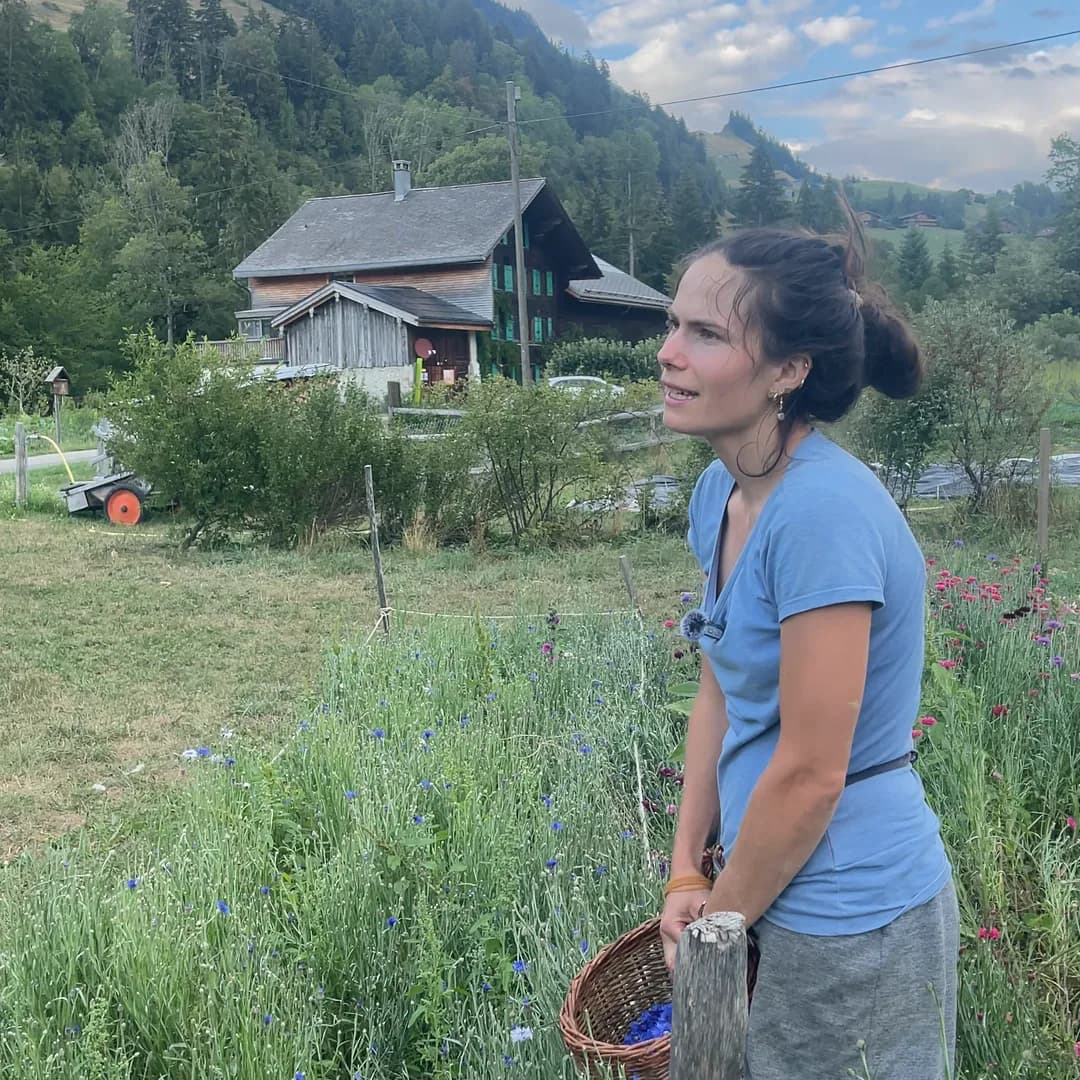 Yaëlle, du Potag’œx, son panier d’osier à la main, le chalet derrière