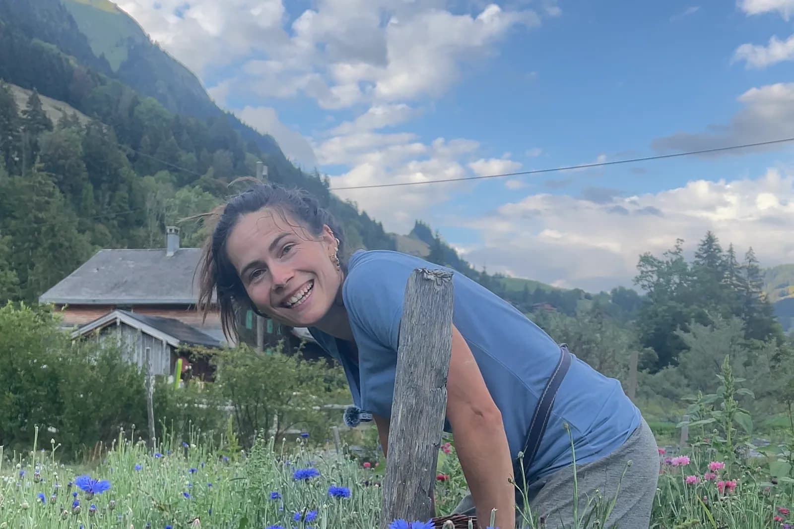 Yaëlle dans le champ de bleuets du Potag’œx, le chalet et la montagne derrière